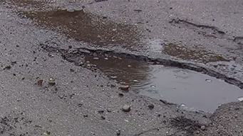 Ein, mit Regenwasser gefülltes, Schlagloch auf einer Straße